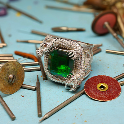 Dragon Ring with Emerald center stone on a workshop table